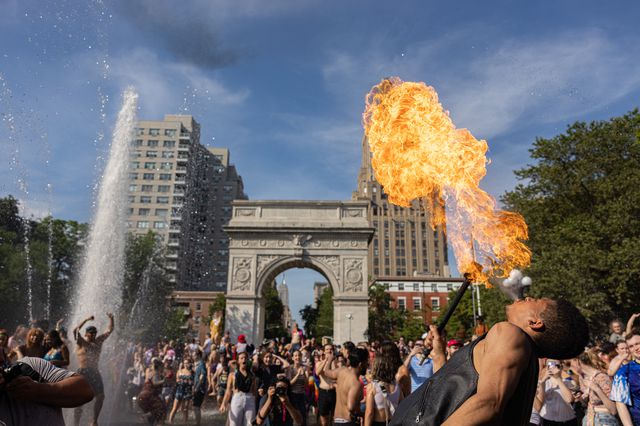 Revelers in Washington Square Park, with one breathing fire into the air,